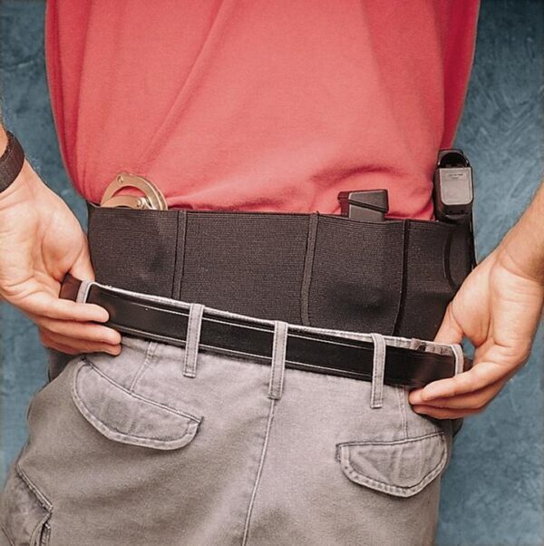 Person adjusting a tactical belt with holsters.