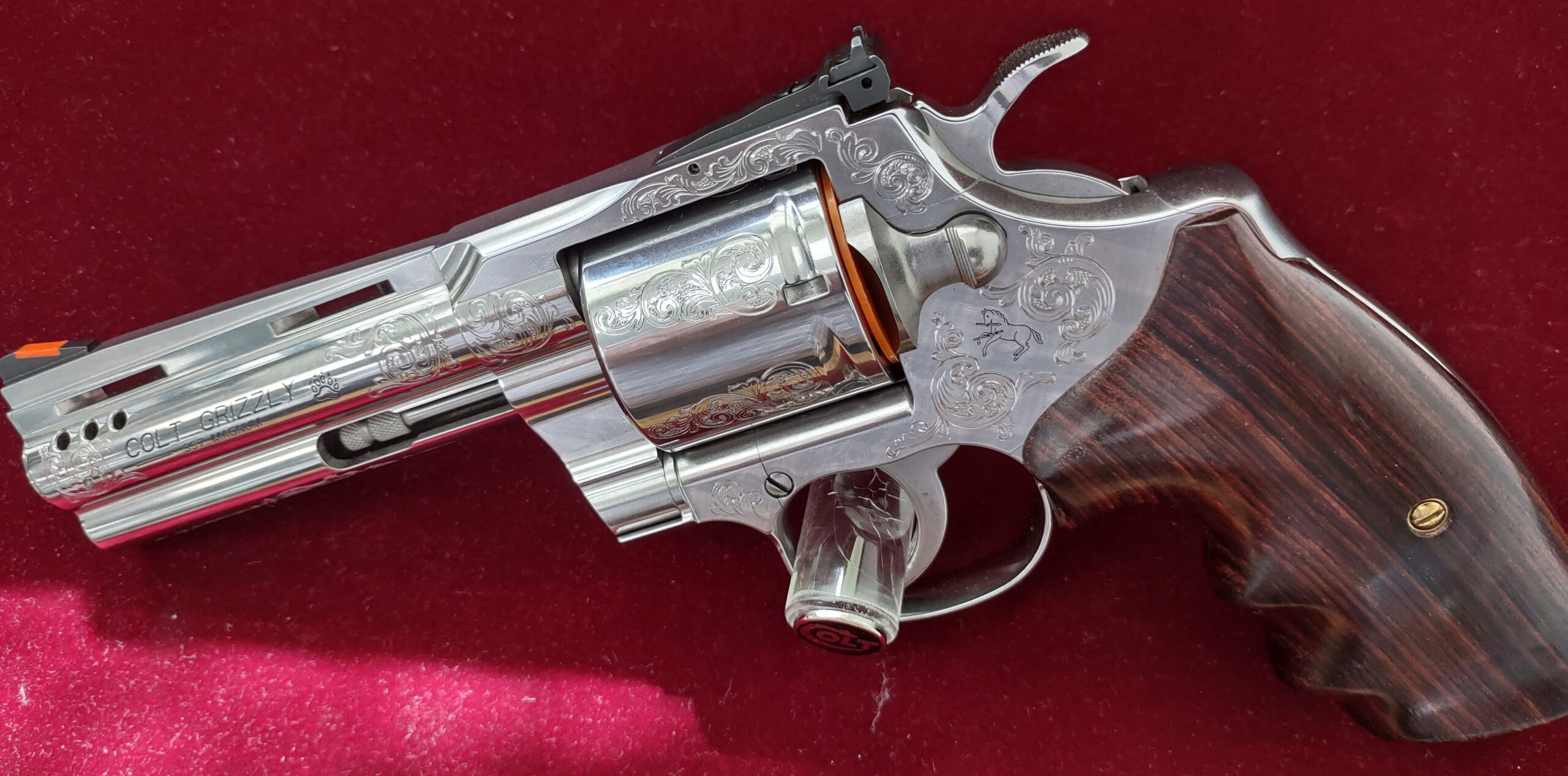 Close-up of a polished revolver on red fabric.