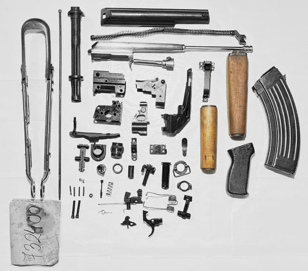 Collection of firearm parts arranged on white background.