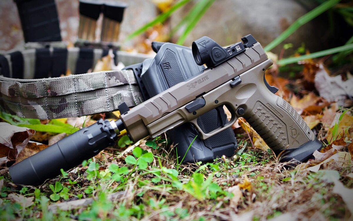 Handgun with suppressor and red dot sight outdoors