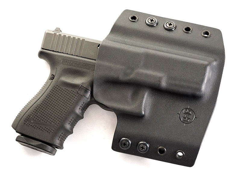 Handgun in black Kydex holster on white background