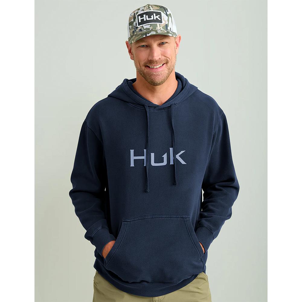 Man wearing navy Huk hoodie and camo cap