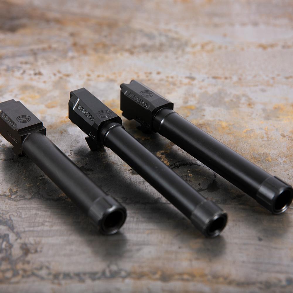 Three black handgun barrels on metal surface