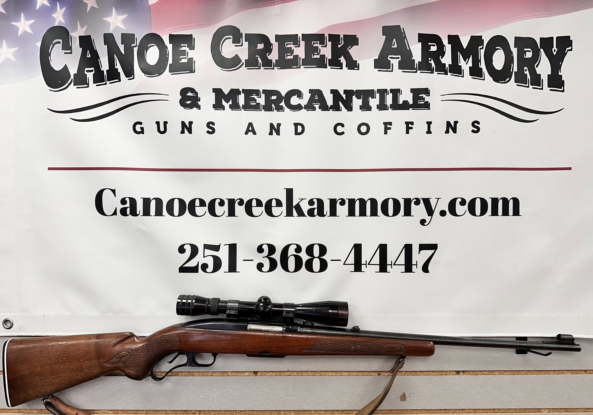 Scoped hunting rifle beneath armory banner