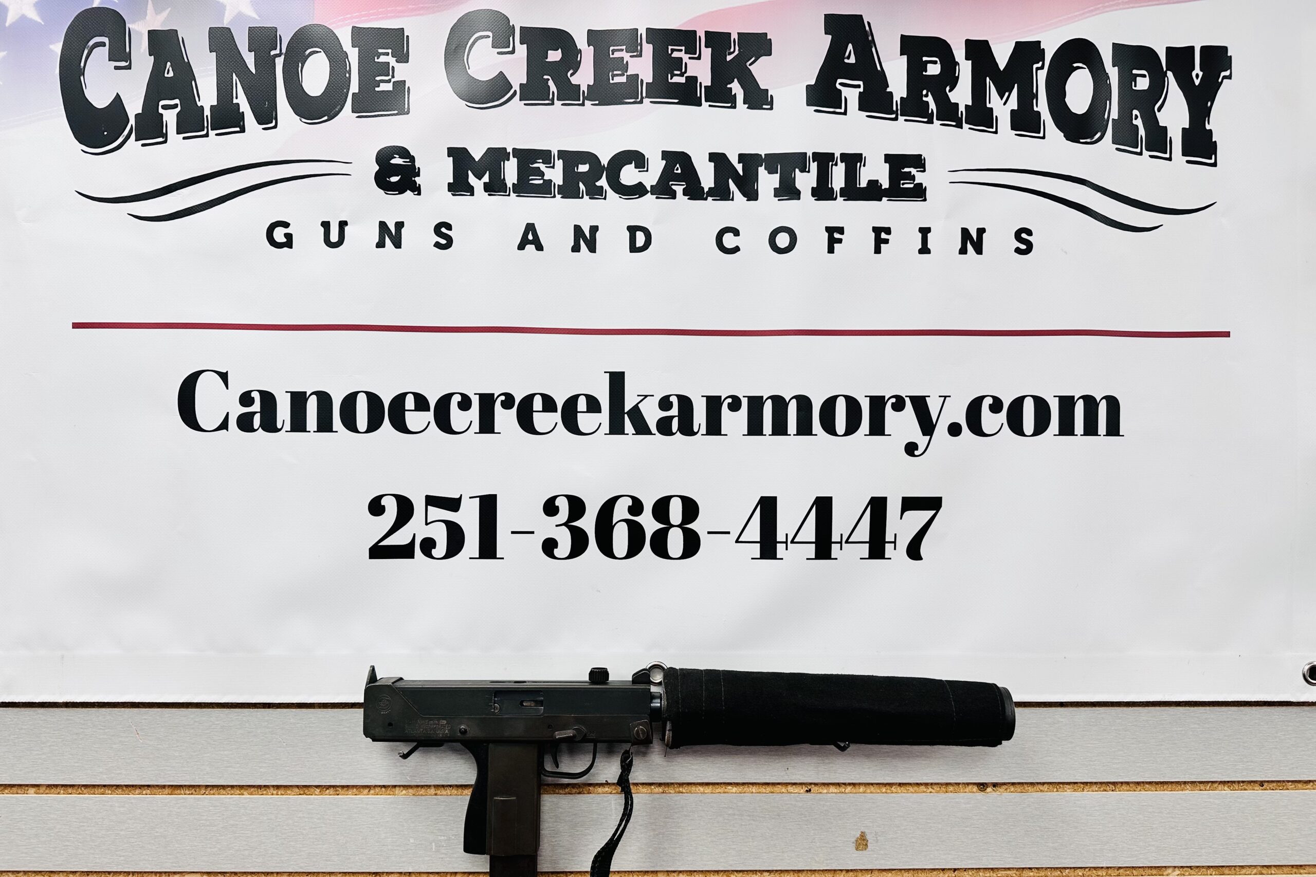 Canoe Creek Armory sign with firearm on counter